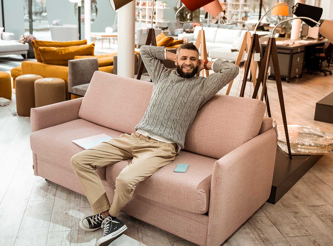 Livraison meuble à domicile. Un homme assis confortablement sur un canapé dans un magasin de meubles.